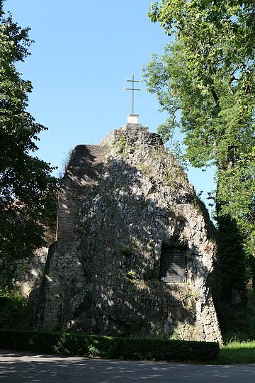 Mangoldfelsen in der Promenade Ein hoher Felsblock trägt ein Kreuz obenauf und eine Inschrifttafel.