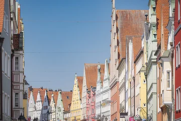 Straße mit bunten, historischen Gebäuden und Satteldächern unter blauem Himmel.